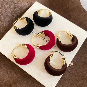 Detailed close-up of velvet C-shape earrings in black, burgundy and brown autumn colors