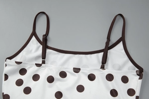 Détail d'un haut blanc à pois avec bordure marron contrastée et fines bretelles