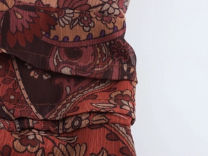 Gros plan sur le motif cachemire dans des tons chauds de marron et rouge avec coutures
