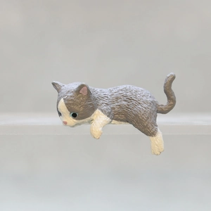 Close-up of a grey and white hanging cat figurine for computer and desk edge decoration