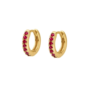 Detail of gold huggie earrings with precision-set red cubic zirconia and a polished finish