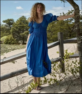 Détail d'une robe longue bleue à manches bouffantes et plis à la taille