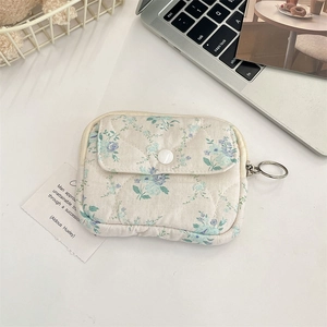 Close-up of quilted floral coin purse featuring main zipper and front button flap pocket