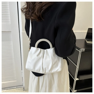 White ruched cloud handbag featuring pearl handle and metal strap on a female model