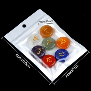 Set of seven 20mm round chakra agate stones with golden yoga symbols on a black background