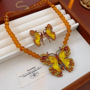 Detailed view of vintage butterfly necklace and earrings set with amber-toned beads