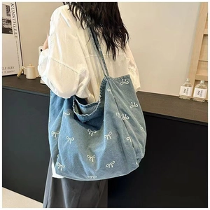 Detailed side view of large blue denim tote bag with white bow pattern on model