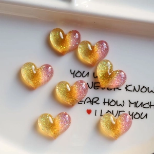 Detail of gradient glitter heart resin charms with yellow and pink colors for DIY crafts