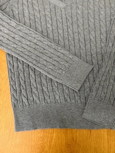 Detailed view of dark grey cable-knit sweater featuring classic V-neck and ribbed texture