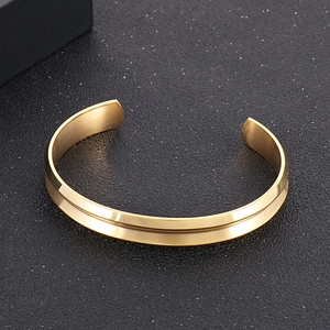 Vista macro del bracciale rigido a C in acciaio inossidabile dorato su base nera