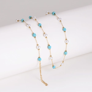 Collana con turchese irregolare e perle con catena dorata su piedistallo bianco