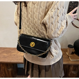 Detail of black glossy small square bag with gold metal twist lock and chunky chain strap