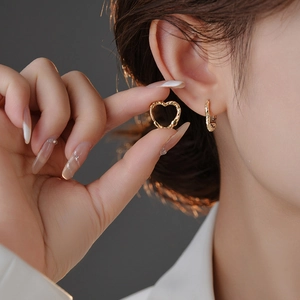 Close-up of heart-shaped gold earrings with unique irregular texture and matte finish