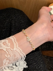 Détail d'un bracelet gourde plaqué or 18k avec perles et cristaux sur un poignet féminin