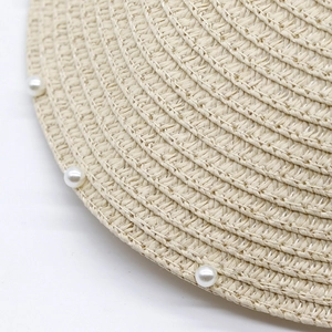 Close-up macro detail of a woven summer straw hat featuring elegant white pearl embellishments