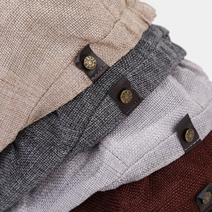 Detail of linen-textured caps with brown leather tags and vintage metal buttons