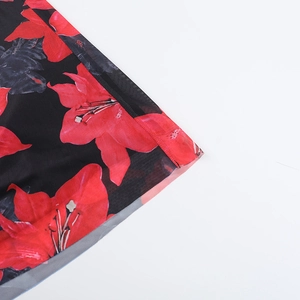 Close-up of red lily floral print on black mesh fabric with rolled hem stitching