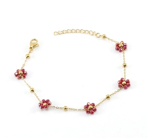 Detail of gold flower bracelet with red faceted beads, lobster clasp and extension chain
