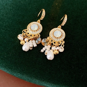 Detail von Vintage-Quastenohrringen mit Perlen und Edelsteinen auf grünem Samt