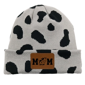 Detail of knit beanie featuring cow print pattern and MOM embossed leather patch