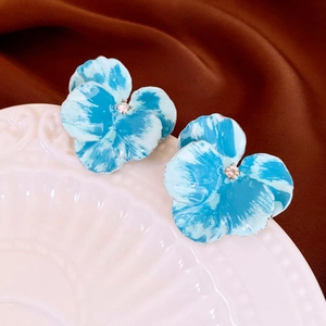 Close-up of pansy flower stud earrings with blue enamel petals and center crystal
