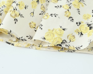 Close-up of floral print midi dress featuring fine hem stitching on off-white poplin fabric