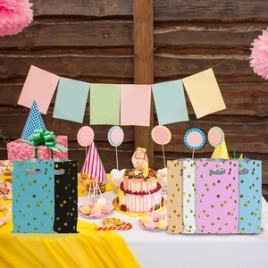 Assorted colorful birthday party gift bags with gold polka dots on festive table setting