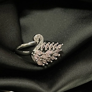 Macro shot of silver swan ring with pink marquise gems and white zirconias on dark silk