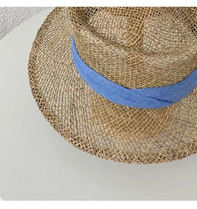 Detail of hand-woven seagrass sun hat featuring natural texture and blue ribbon band