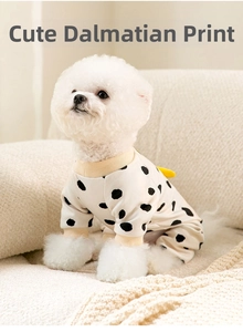 Detailed close-up of cow print pet pajamas with soft yellow ribbed cuffs on a white dog
