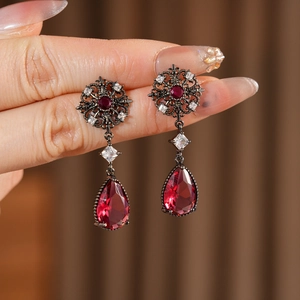 Gros plan de boucles d'oreilles vintage en forme de goutte d'eau avec pierre rouge et diamants