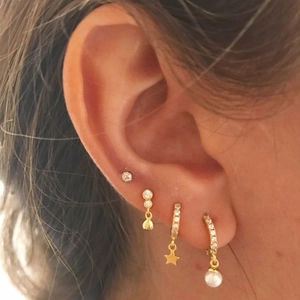 Close-up of gold star and pearl earrings set with cubic zirconia on a model