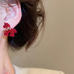 Close-up of red flocked poodle stud earring with golden bow detail on model's ear
