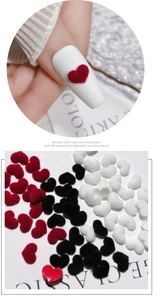 Macro shot of 3D velvet heart nail charms in red, black, and white for manicures