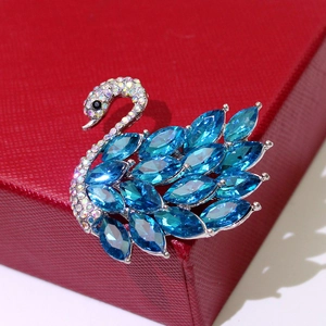 Close-up of a silver swan brooch featuring marquise-cut blue crystals and small rhinestones