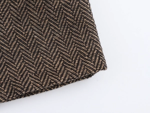 Gros plan sur la texture en laine à chevrons marron et noir d'une veste courte chic