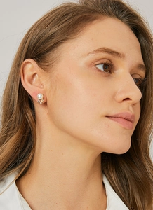 Close-up of pearl stud earring with three zircon stones on gold base worn by a model