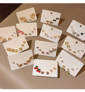 Detailed set of cute gold-toned earrings with butterfly, cherry, and bear motifs