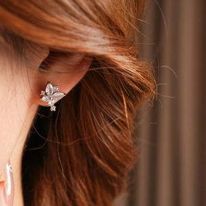 Détail d'une boucle d'oreille papillon argentée avec cristaux sur l'oreille