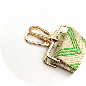 Close-up of golden metal hooks and adjustable buckle on beige and green woven strap