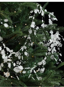 Macro view of crystal snowflakes hanging on a Christmas tree with warm bokeh lighting