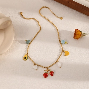 Flat lay of a gold beaded necklace with strawberry, avocado, banana and heart charms