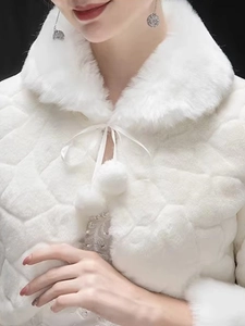 Close-up of white faux fur bridal shawl with plush collar and pom-pom tie closure