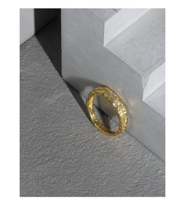 Macro detail of gold S925 silver ring with hammered texture and two cubic zirconia gems