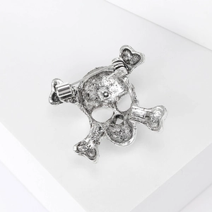 Macro view of the silver skull brooch back showing secure safety pin and metal texture