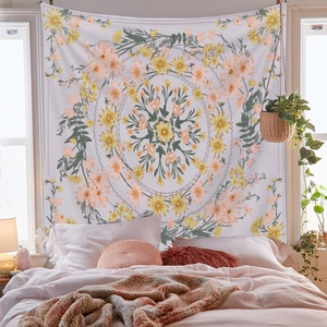 Detail of bohemian mandala tapestry with yellow and orange floral patterns over a cozy bed