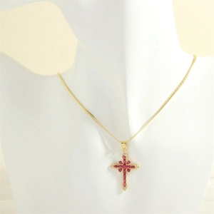 Detail of 18K gold cross necklace featuring red oval stones and white cubic zirconia