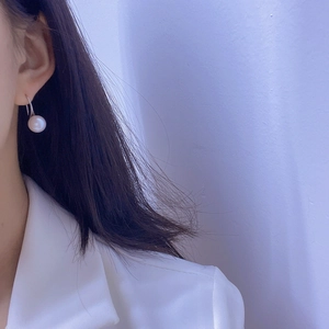 Close-up of elegant single white freshwater pearl drop earring with silver metal hook