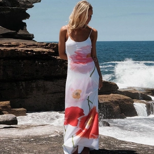 Detail of floral print maxi dress featuring red poppy patterns against a coastal backdrop