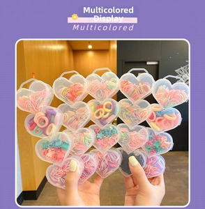 Close-up of heart-shaped box filled with colorful elastic hair bands and flower clips